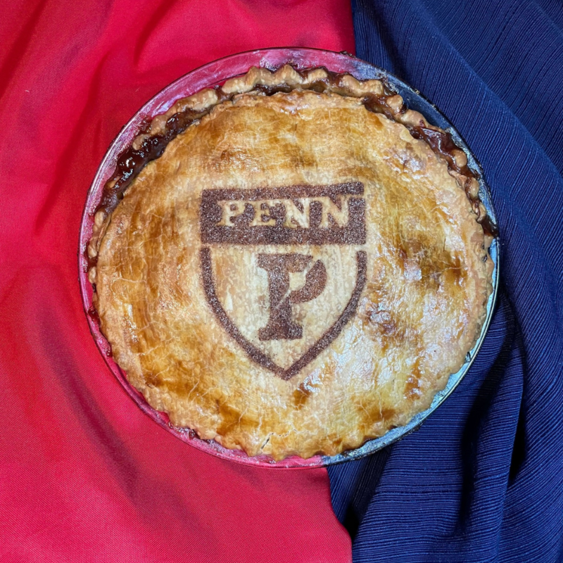 A pie on a red and blue backdrop with the Penn Athletics logo baked into it