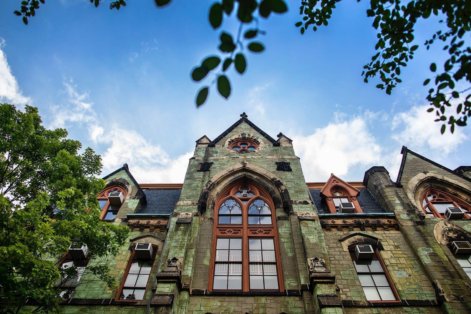 College Hall facade, showing collegiate gothic architecture, framed by mature trees