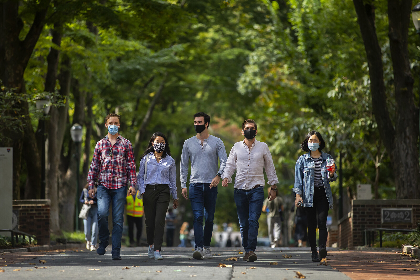 five students walking down locust walk with masks