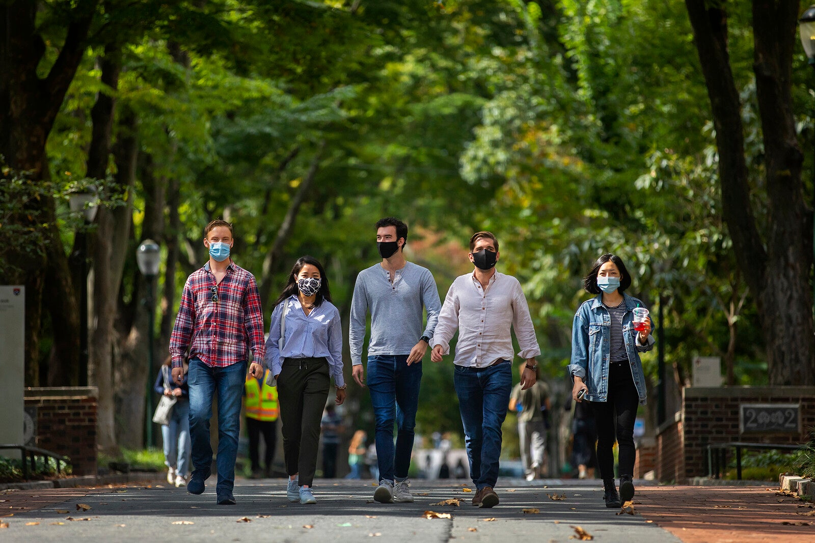 five students walking down locust walk with masks