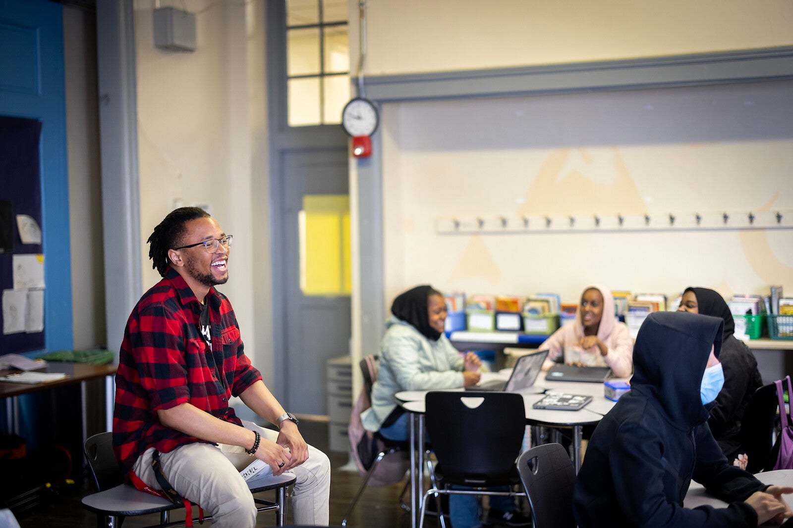 tamir harper sitting on a desk and smiling at students