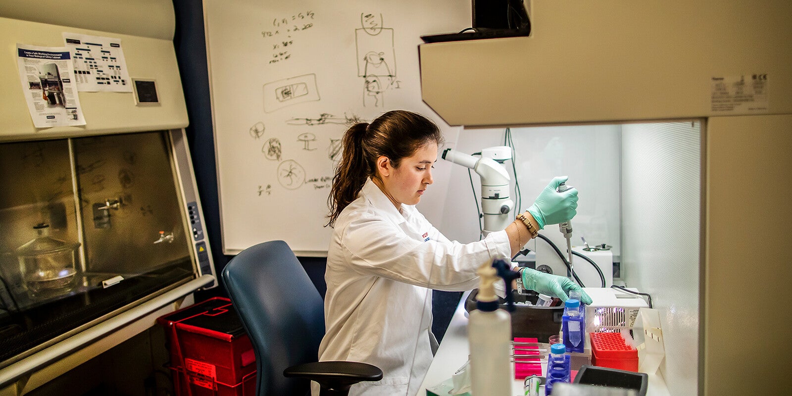 A woman in a lab in front of a microscope