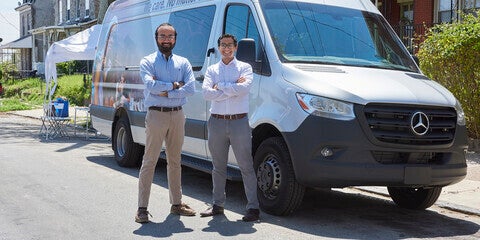 Two people in front of a van