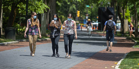 Students wearing masks walking down locust walk