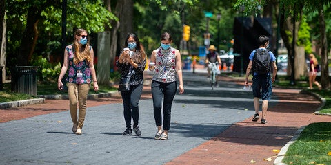 Students wearing masks walking down locust walk