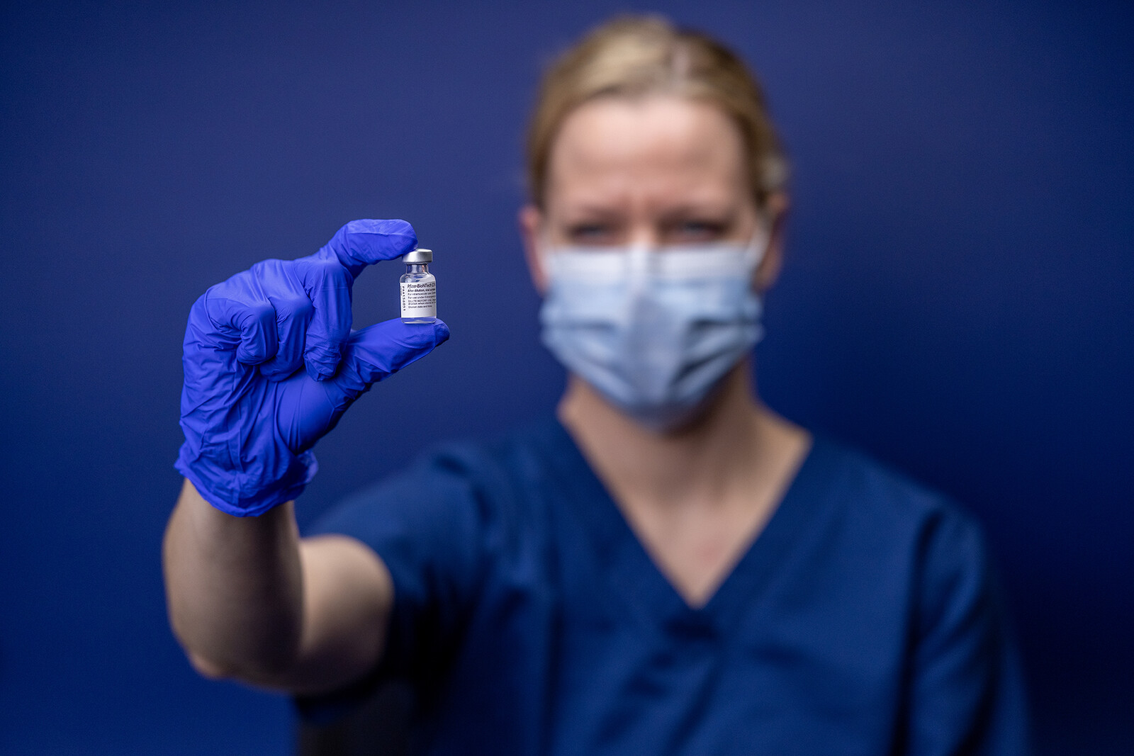 nurse holding covid vaccine in gloved hand