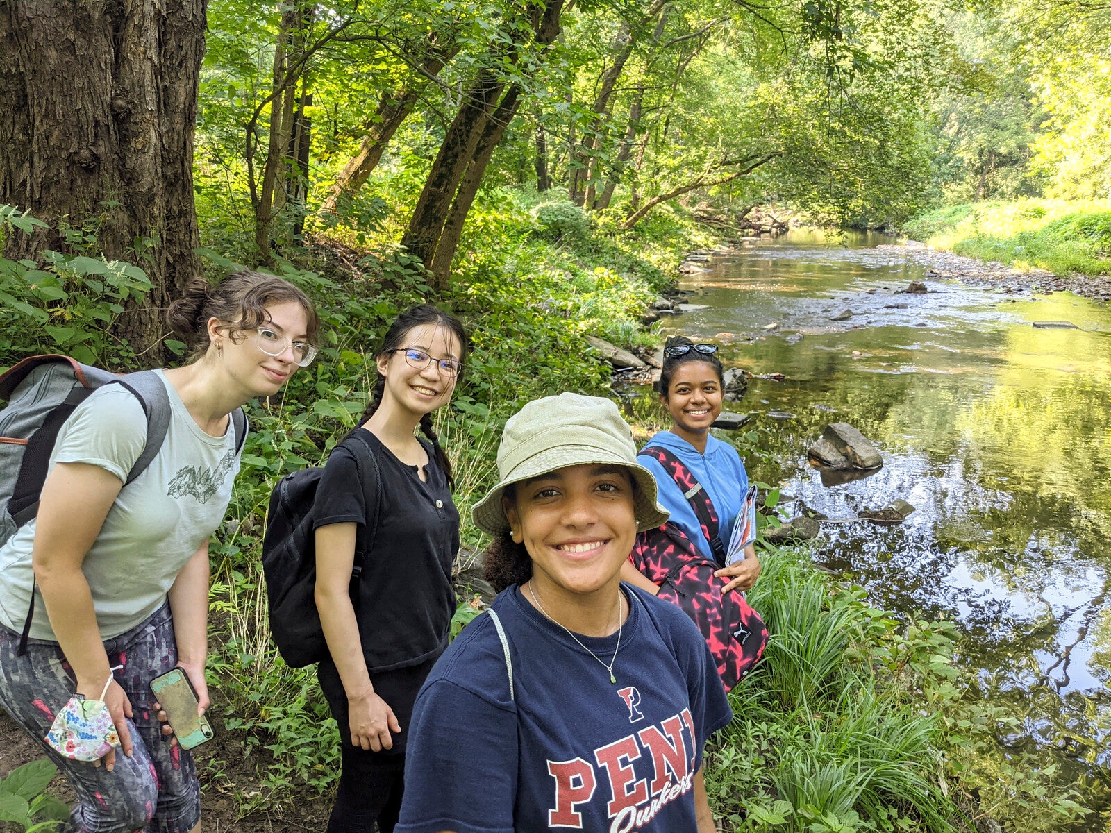 Anna Balfanz of the Netter Center, junior Ayana Shirai, and sophomores Mya Gordon and Yasmin Abdul Razak along the banks of Cobbs Creek. (Image: Courtesy of Pablo Cerdera)  