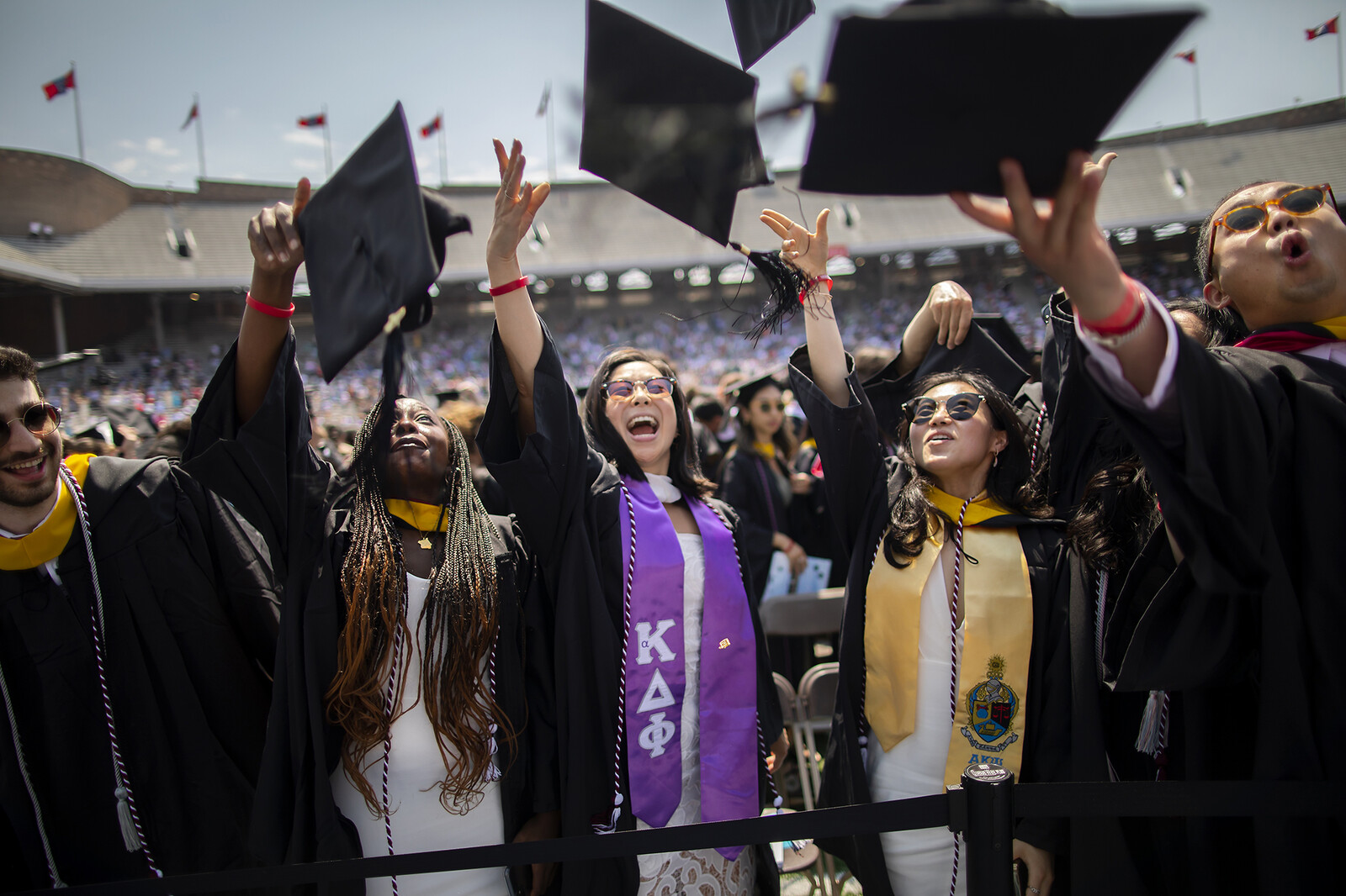 graduates throw caps up in the air at commencement