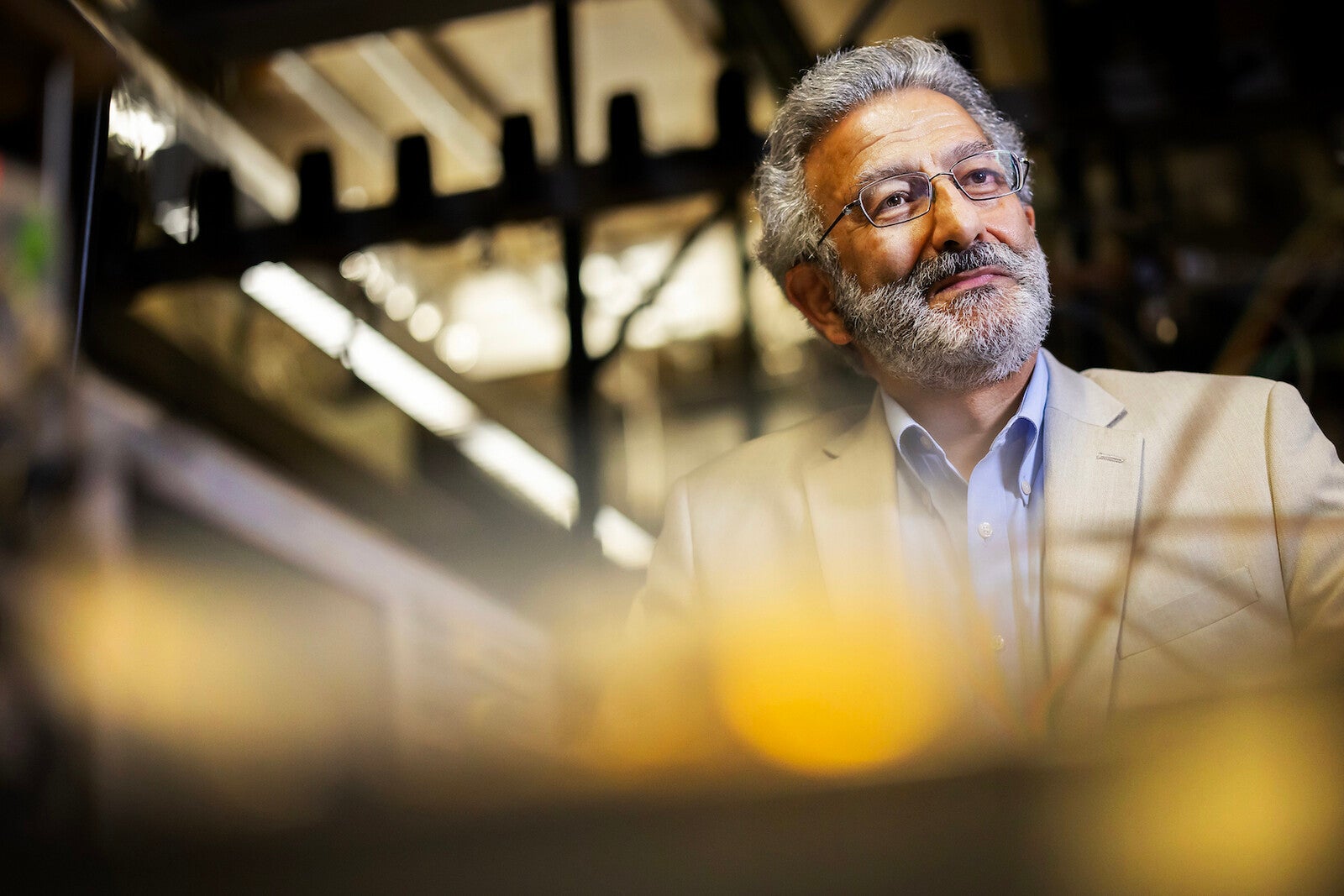 nader enheta sitting in his lab with engineering equipment in the foreground and background