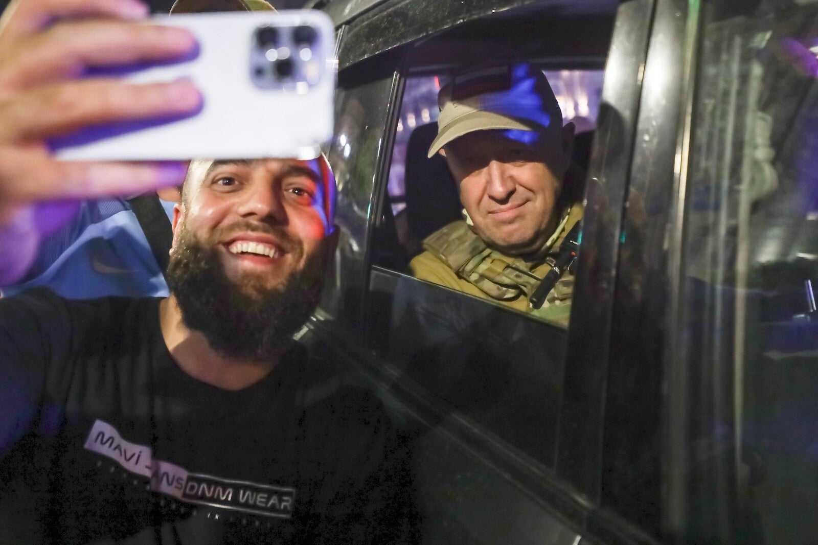 Yevgeny Prigozhin sitting in a car while a person takes a selfie with him