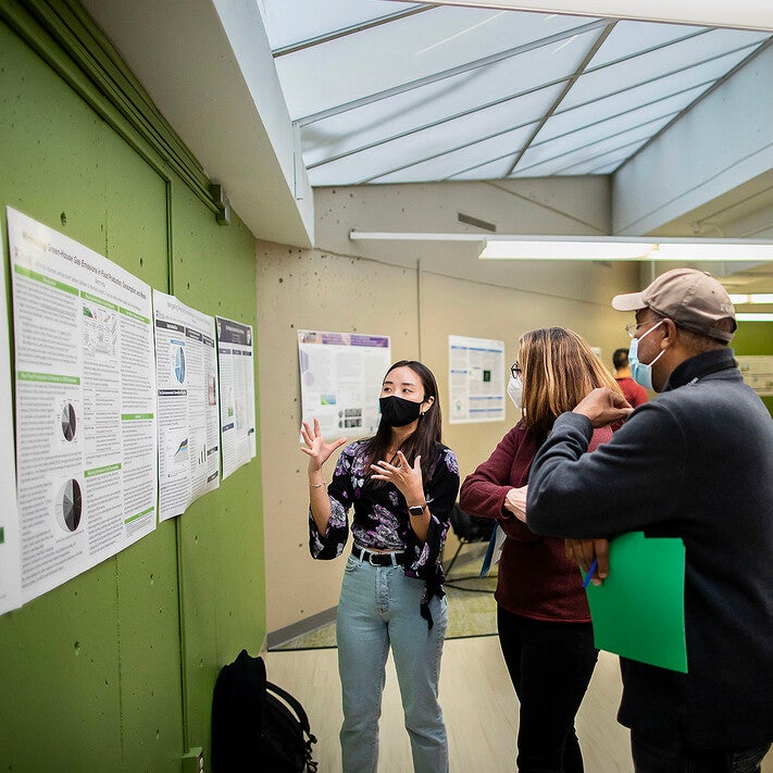 A student presents their work during a poster session in the 'Humans and the Earth System: How it Works, How We Got Here, and How to Save Our Planet' class.