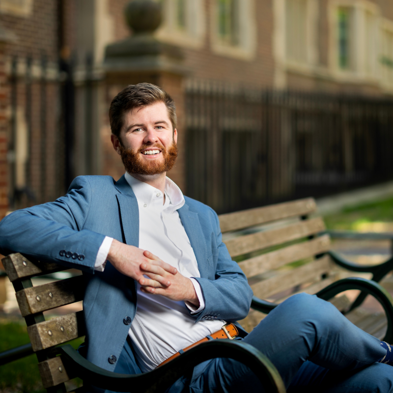 Chip Chambers sitting on a bench on the University of Pennsylvanias campus smiling for a posed photo.