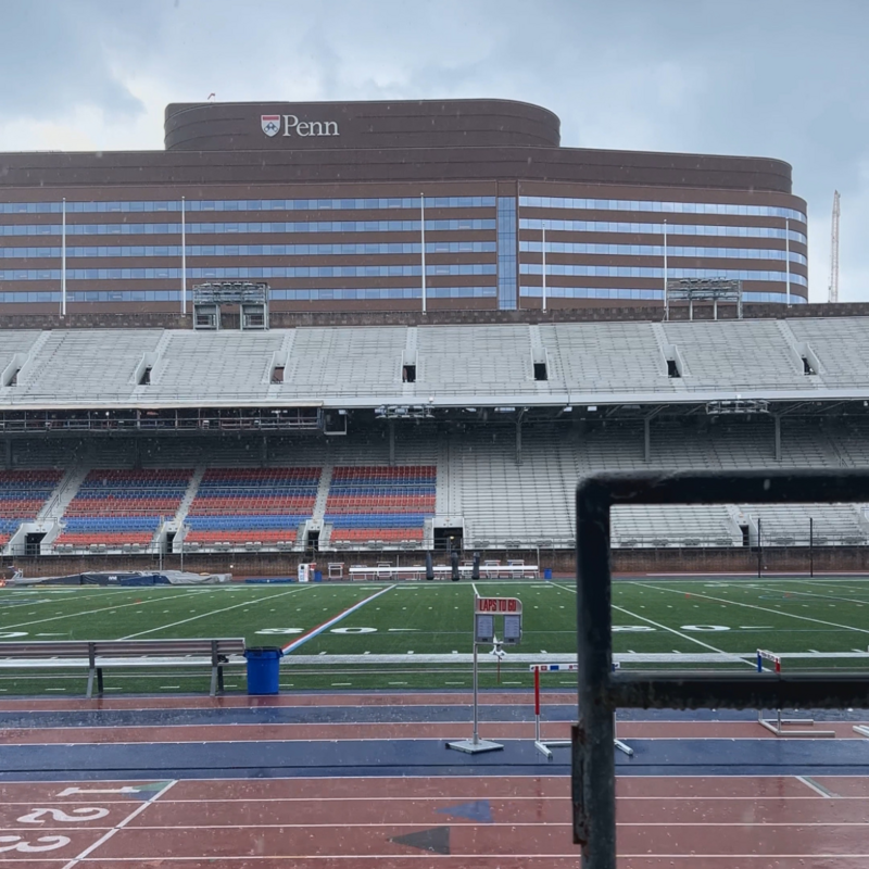 A view of Franklin Field from the stands during a rain storm with the Hospital of the University of Pennsylvania in the background